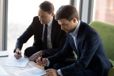 Photo of 2 businessmen signing a partnership agreement